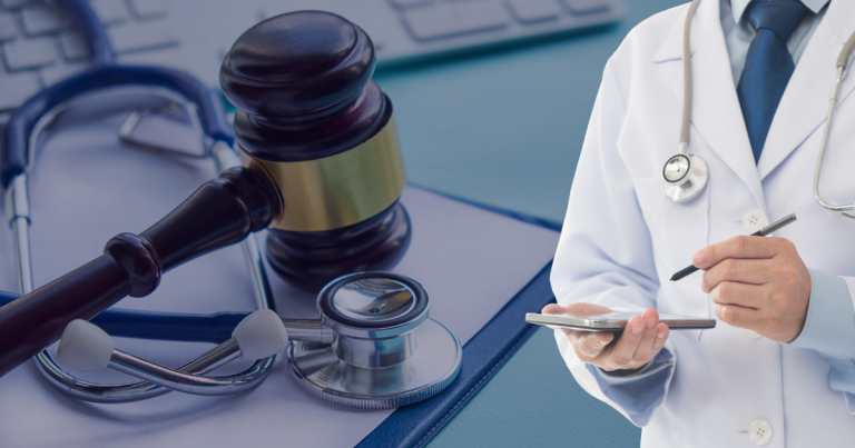 A gavel and a stethoscope is placed on top a document and a doctor writing prescription